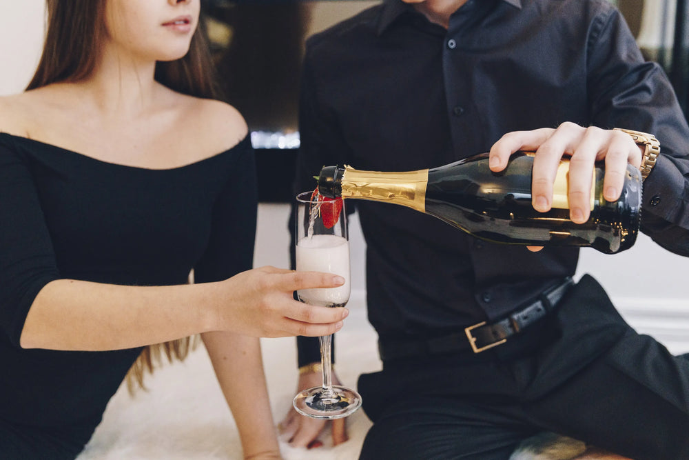Person pouring champagne into a glass held by another person.