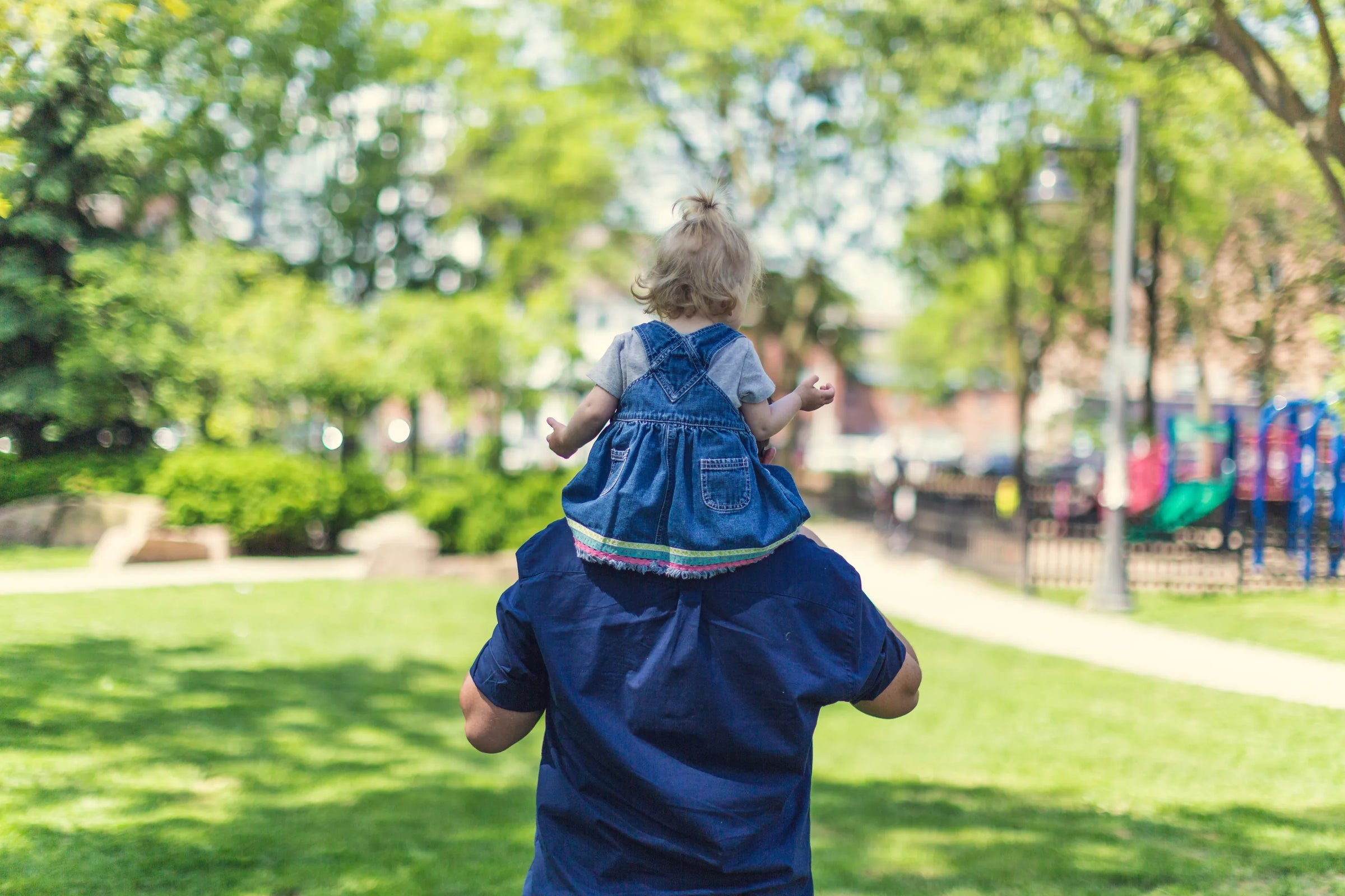 Person carrying a child on shoulders in a park