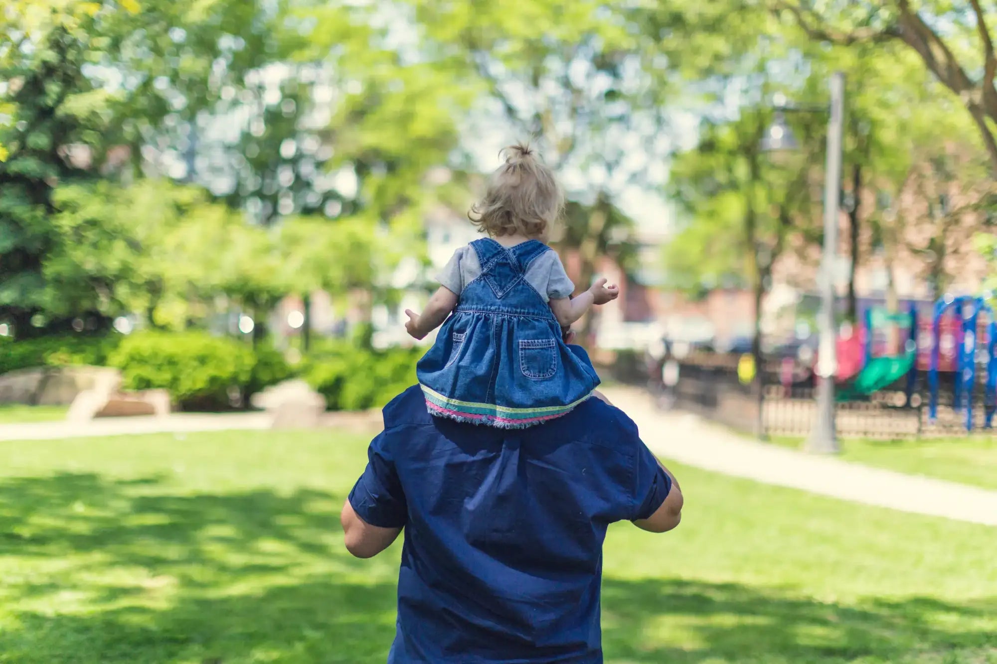 Person carrying a child on shoulders in a park